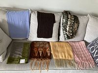 Seven assorted scarves laid out on sofa