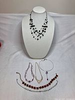 All six necklaces displayed on bust and table