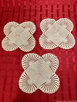 Three matching crocheted doilies displayed on red background