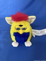 Front view of yellow Furby with red mane and blue beard