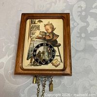 Front view showing Hummel illustration, dial and chains