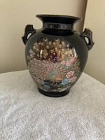 Full view of black porcelain vase front with peacock and floral design