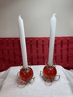Both candle holders with white tapers inserted, front view
