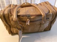 Top view showing tan leather duffle with carry handles and front pocket