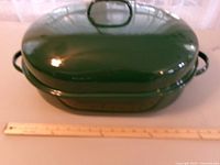 Top view of closed green enamel roasting pan with ruler for scale