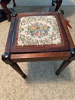 Overall view of wooden footstool showing legs and needlepoint seat