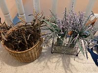 Metal caddy holding two glass vases with artificial lavender and clear filler beads, wicker basket with faux foliage beside it