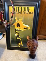 Framed Afrique Occidentale Francaise poster, beaded necklace draped over frame, carved wooden giraffe mask in front