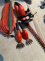 Overview showing hedge trimmer, two handheld shears and coiled extension cord