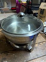 Full view of stainless steel round chafing dish with glass lid on stand
