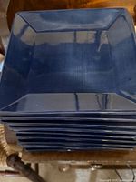 Stack of square dark-blue plates showing top and rim