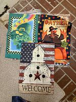 Three un-packaged flags showing shamrock, turkey, and rustic barn designs