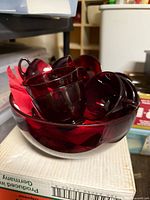Ruby red glass punch bowl containing matching cups