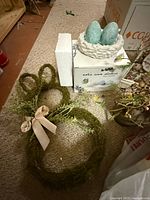 Bunny wreath, bird nest with eggs, styrofoam block and packaging visible
