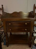 Front view of wood washstand showing drawer, turned legs and lower shelf