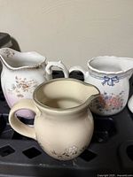 Three pitchers: cream floral, pink fade floral, scalloped rim floral