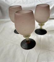 Three frosted purple mauve ombré wine glasses standing upright