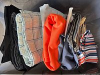 Bin containing folded fabric pieces: black, plaid, floral, orange, grey, striped