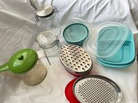 Group shot of all kitchen items: grater set, Tupperware containers, glass jars, jug