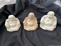 Front view of the three ceramic Buddha statues showing size and color variation
