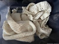 Bin containing two unfinished off-white knitted pieces