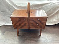 Closed wooden cantilever sewing box on legs