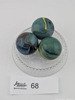 Three marbles on glass dish with lot tag visible