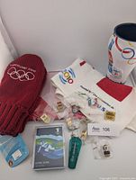 Full lot overview showing toque, towel, tumbler, keychain, packaged card and pins