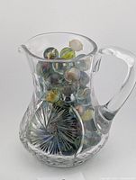 Full view of crystal pitcher filled with marbles