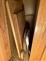 Stacked wooden and plastic cutting boards inside cabinet