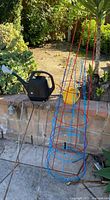 Lot overview with black watering can, tomato cages, hooks