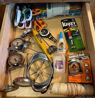 Drawer view showing scissors, thermometers, apple slicer, cutter, adhesives, twine, straw package