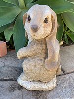 Full view of standing lop-eared rabbit sculpture on outdoor stone surface