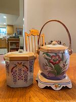 Both biscuit jars side by side on table, showing shapes, lids and underplate