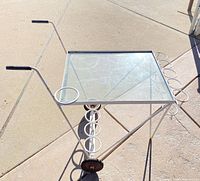 Overall view of white metal bar cart showing glass top, bottle rings, wheels and handles