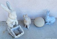 overview of four items: two concrete rabbits, concrete sphere, ceramic rabbit