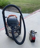 Ridgid shop vacuum with hose and wands beside compact air compressor