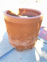 Full view of terracotta planter showing overall shape, rim pattern and surface wear