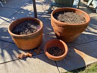 Three terracotta planters on patio showing relative sizes and crack pieces