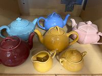 Group shot of five teapots, creamer, sugar bowl