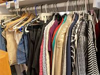 Full clothing rack with assorted jackets, tops, skirts and pants on hangers