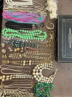 Overall lot view showing assorted necklaces, earrings, brooches, bracelets and jewelry box