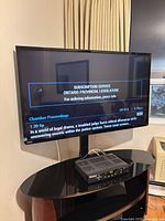 Front view of 50" Toshiba TV displaying content, mounted on wall bracket with remote visible on shelf below