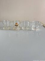 Front view of four miniature beer stein shot glasses in a row