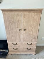 Front view of light wood armoire dresser showing two doors and two drawers