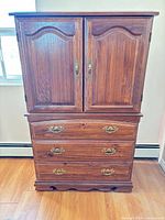 Front view of closed dresser showing two doors and three drawers