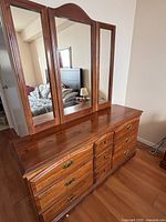 Front view of wooden dresser with attached tri-panel mirror