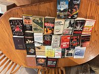 Overhead shot of 27 paperback books arranged spine-up on a wooden table