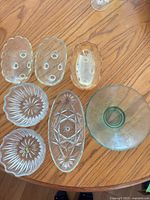 All seven small pressed glass serving dishes arranged on wooden surface