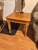 angled view of solid wood side table beside chair